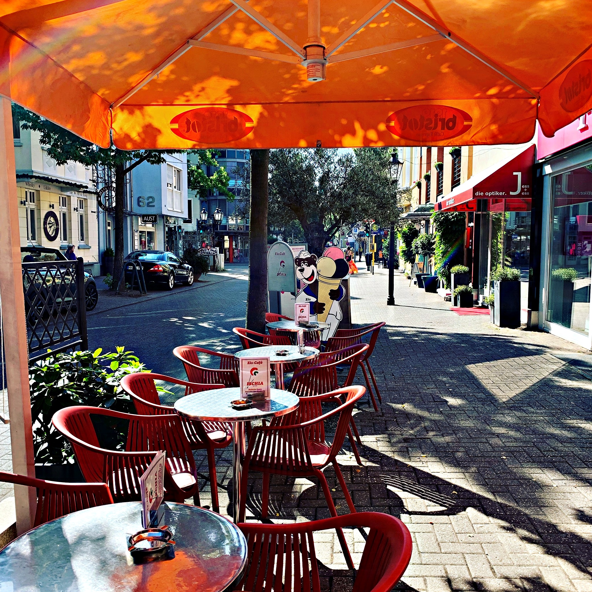 Außenplätze des Eiscafés Ischia unter einem Sonnenschirm auf der Düsseldorfer Straße in Saarn